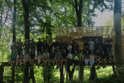 Teilnehmende und Tutor*innen des Summer Build 2026, sitzen auf «The Datum», im Hintergrund das im Rahmen dieses Programms errichtete Projekt «The Wild Thing», Photo by Daniella Diaz Lamboglia.