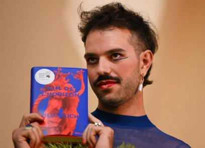 Porträtaufnahme von Kim de l'Horizont, der sein Buch «Blutbuch» in den Händen hält.