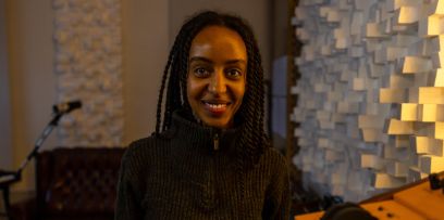 Portrait von Nabyla-Amani Serag. Die junge Frau blickt im Tonstudio der Band Sirens of Lesbos direkt in die Kamera. Nabyla lacht.