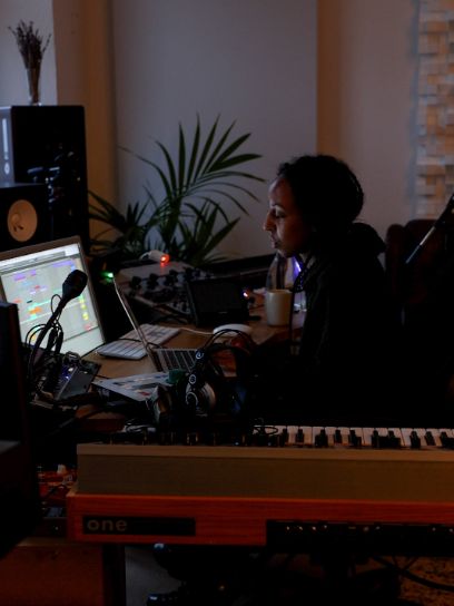 Nabyla-Amani Serag sitzt in ihrem Tonstudio vor einem Bildschirm. 