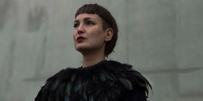 Regina Dürig, kurze Haare, schwarzes Oberteil im Portrait vor einer unscharfen grauen Wand