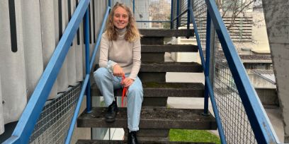 Eine blonde Frau sitzt auf einer Treppe mit blauem Geländer.
