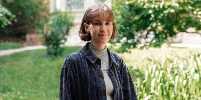 Portrait von Lena Thomma. Die junge Frau blickt im Garten vor dem Schweizerischen Literaturinstitut in Biel direkt in die Kamera.