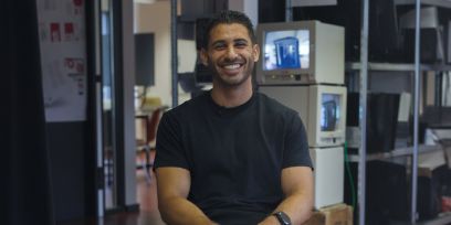 Portrait von Rabih Haj-Hassan. Der junge Mann sitzt im Atelier am Holzikofenweg in Bern und lacht in die Kamera