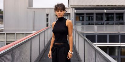 Eine junge Frau schaut in die Kamera. Sie trägt dunkle Kleider.