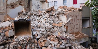 Ein halbabgerissenes Haus. Zu sehen sind viele Bruchstücke, auf einer Wand steht «BYE BYE».