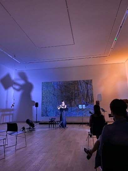 Raum in orange-blauen Tönen, Yvonne Gisler spielt ein Instrument, dunkler Raum 