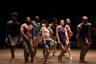 Menschen tanzen auf einem Parkett. Dabei sind die Hände am Körper angelegt.