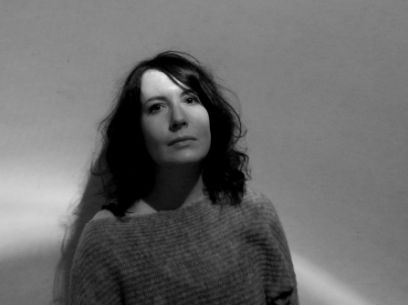 Weichgezeichnete Porträtaufnahme in Schwarzweiss  einer Frau mit langen, dunklen Haaren.