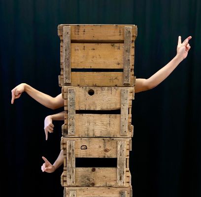 Holzkisten gestapelt aus denen Arme in verschiedene Richtungen zeigen