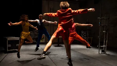 Foto mit vier Tänzer*innen in dunklem Raum, Personen leicht beleuchtet