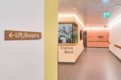 Ein Eingangsbereich eines Spitals. Zu lesen ist Station Nord. Der Bereich ist hell in den Farben gelb, orange und weiss.