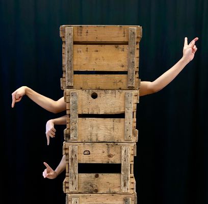 Holzkisten gestapelt aus denen Arme in verschiedene Richtungen zeigen