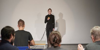 Eine in Schwatz gekleidete Person steht verkabelt vor einer weissen Wand