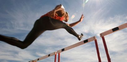 Ein Sportler springt über eine Hürde.