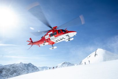 Regahelikopter schwebend über alpinem Schneefeld