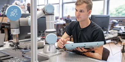 Männliche Person programmiert im Labor einen Greifroboter für Kleinteile