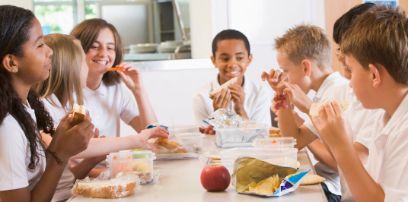 Kinder essen gemeinsam am Tisch.
