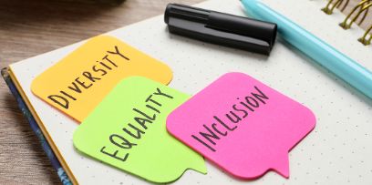 Notizzettel mit Worten Diversity, Equality, Inclusion liegen auf einem Heft