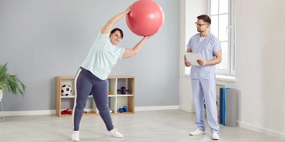 Übergewichtige Frau macht mit Physiotherapeuten Übungen