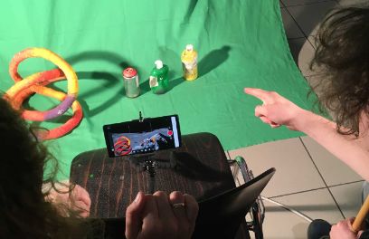 Zwei Menschen Fotografieren Gegenstände mit dem Smartphone auf einem grünen Tuch.