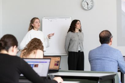 two female students presenting in front of a whiteboard