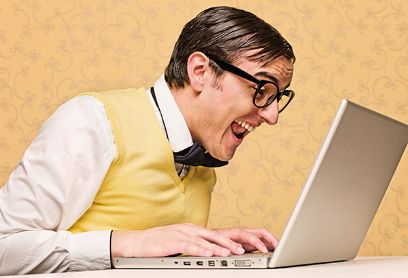 Mensch mit schwarzer dicker Brille schaut begeistert in den Laptop