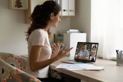 Eine Frau sitzt vor Laptop an einem Online-Meeting oder einer Online-Weiterbildung