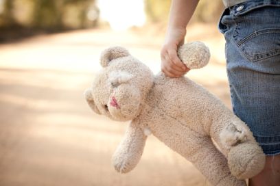 Kind mit lädiertem Teddy auf der Landstrasse
