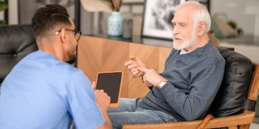Pflegefachmann spricht mit älterem Patienten