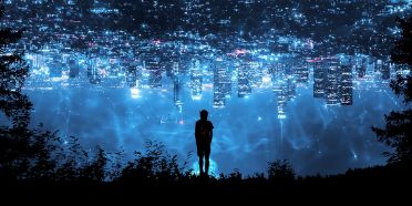 Es ist ein surreales Bild, bei dem der Schatten eines Mannes zu sehen ist, der am Ufer eines Sees steht. An der Wasseroberfläche spiegelt sich eine Skyline mit Wolkenkratzern.